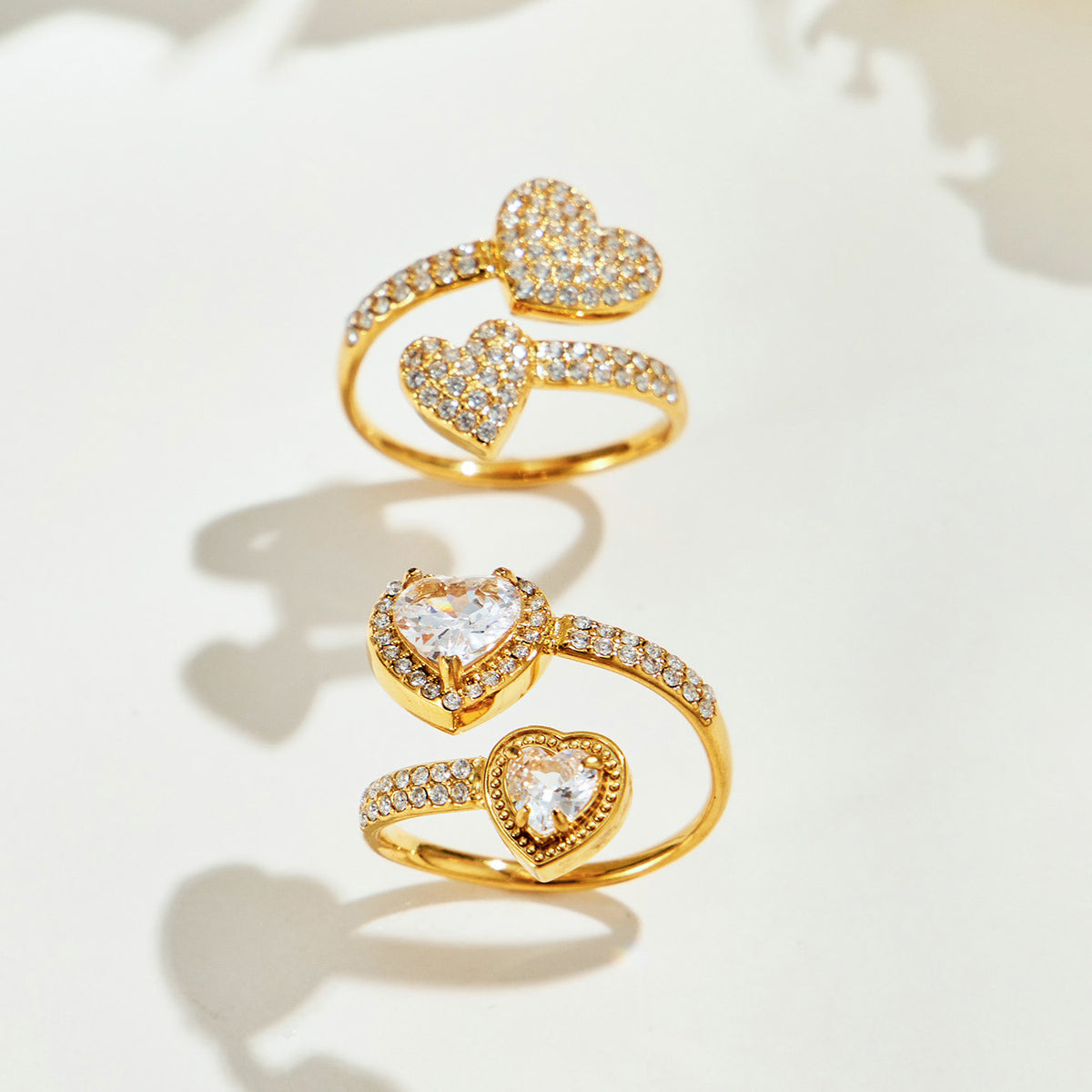 Gold-tone pave-heart and double-heart halo rings displayed together, showing their different stone details