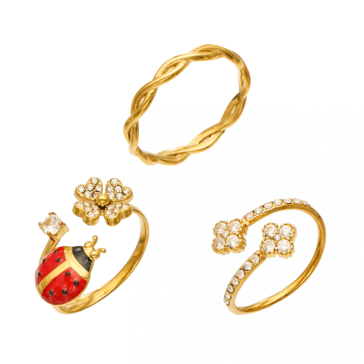 Three gold-tone stainless steel rings on a white background, featuring a red ladybug and flower, double flowers and a twisted band