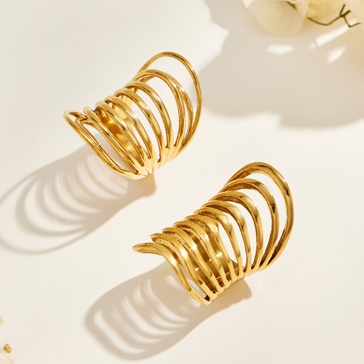 Angled view of two gold-tone stainless steel rings showing elongated profiles and graduated curved bands