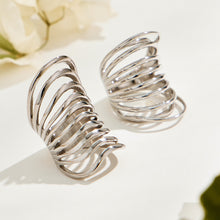 Two silver-tone stainless steel openwork rings displayed in natural light, showing their sweeping curved bands