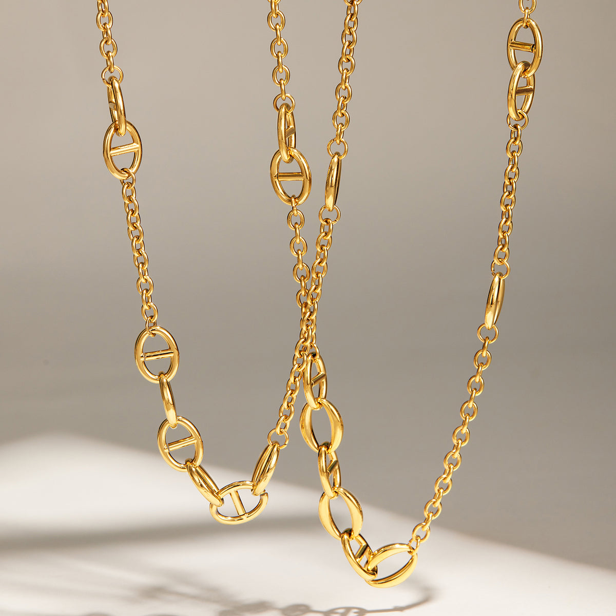 Stainless steel oval link necklaces with gold plated finish displayed hanging