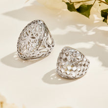 Silver-tone stainless steel floral and lattice rings displayed together on an ivory surface