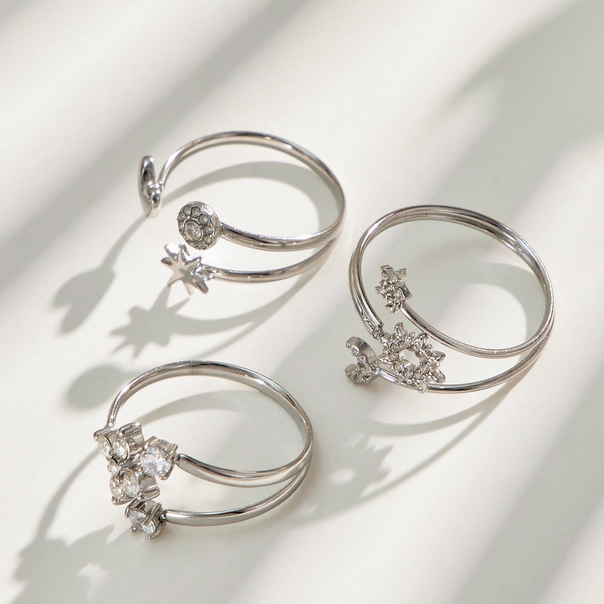 Three steel-tone stainless steel open rings arranged on a light surface with soft shadows