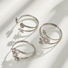 Three steel-tone stainless steel open rings arranged on a light surface with soft shadows