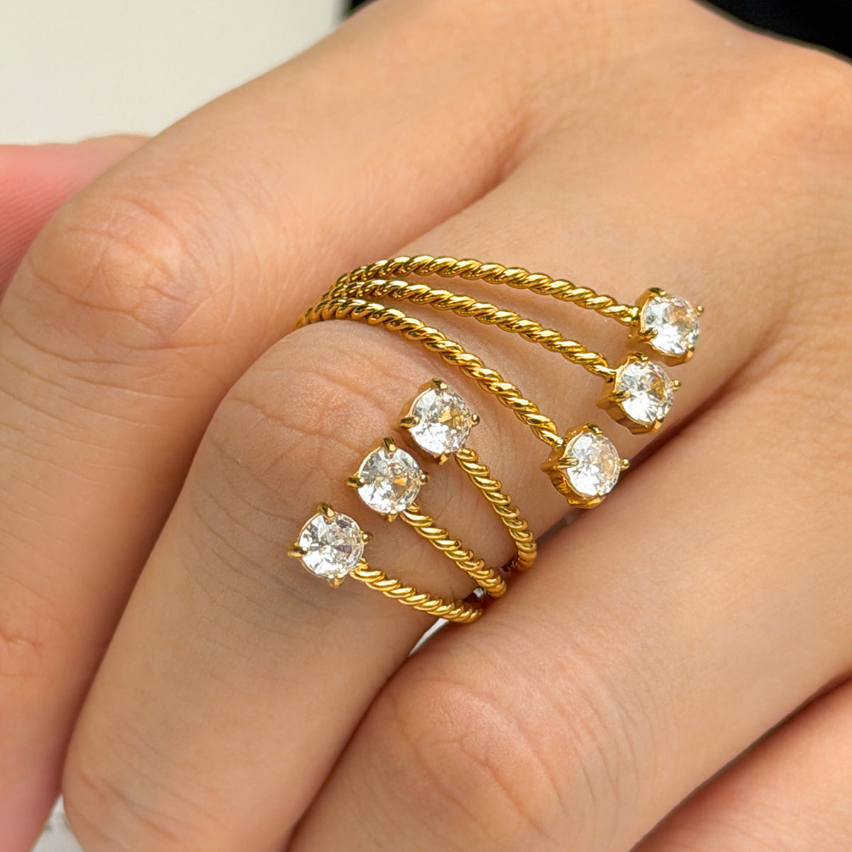 A420 gold-tone stainless steel ring worn on a finger, with three textured bands ending in clear stone settings