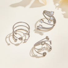 Three steel-tone stainless steel triple-band open rings arranged on a cream surface