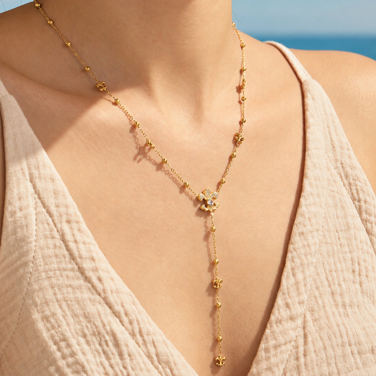 Gold-tone stainless steel Y lariat necklace worn alone, with ornamental details and a long beaded chain drop