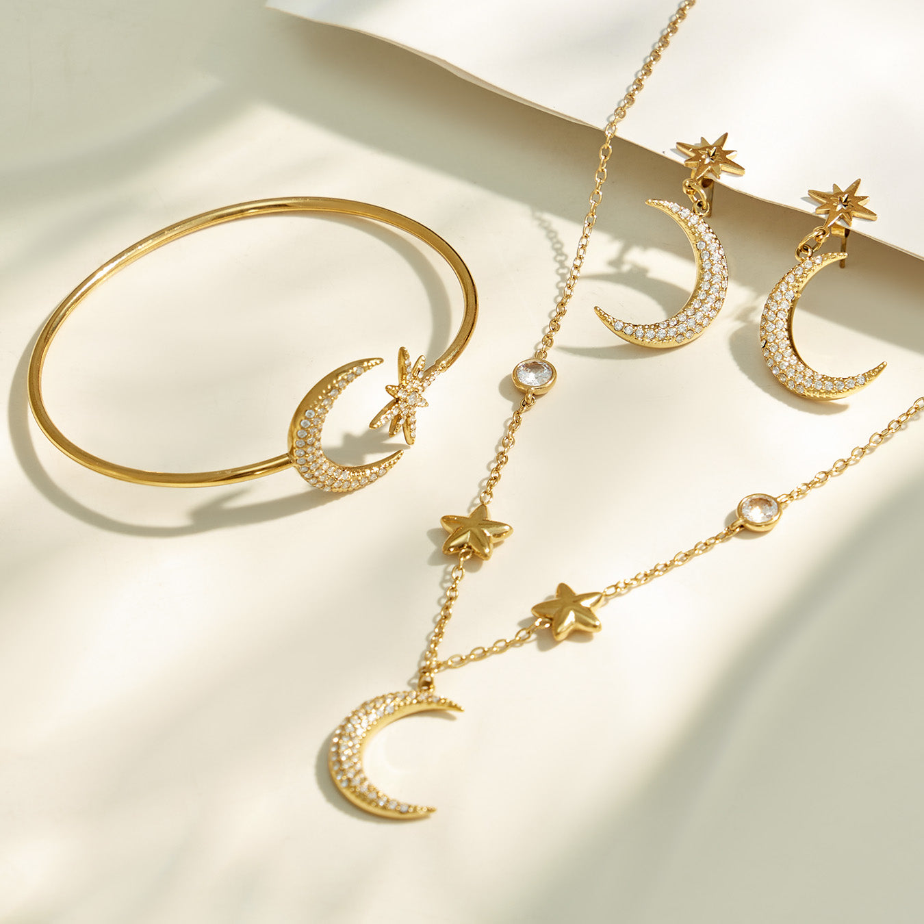 Gold star and moon necklace and cuff bracelet arranged together in a flat lay