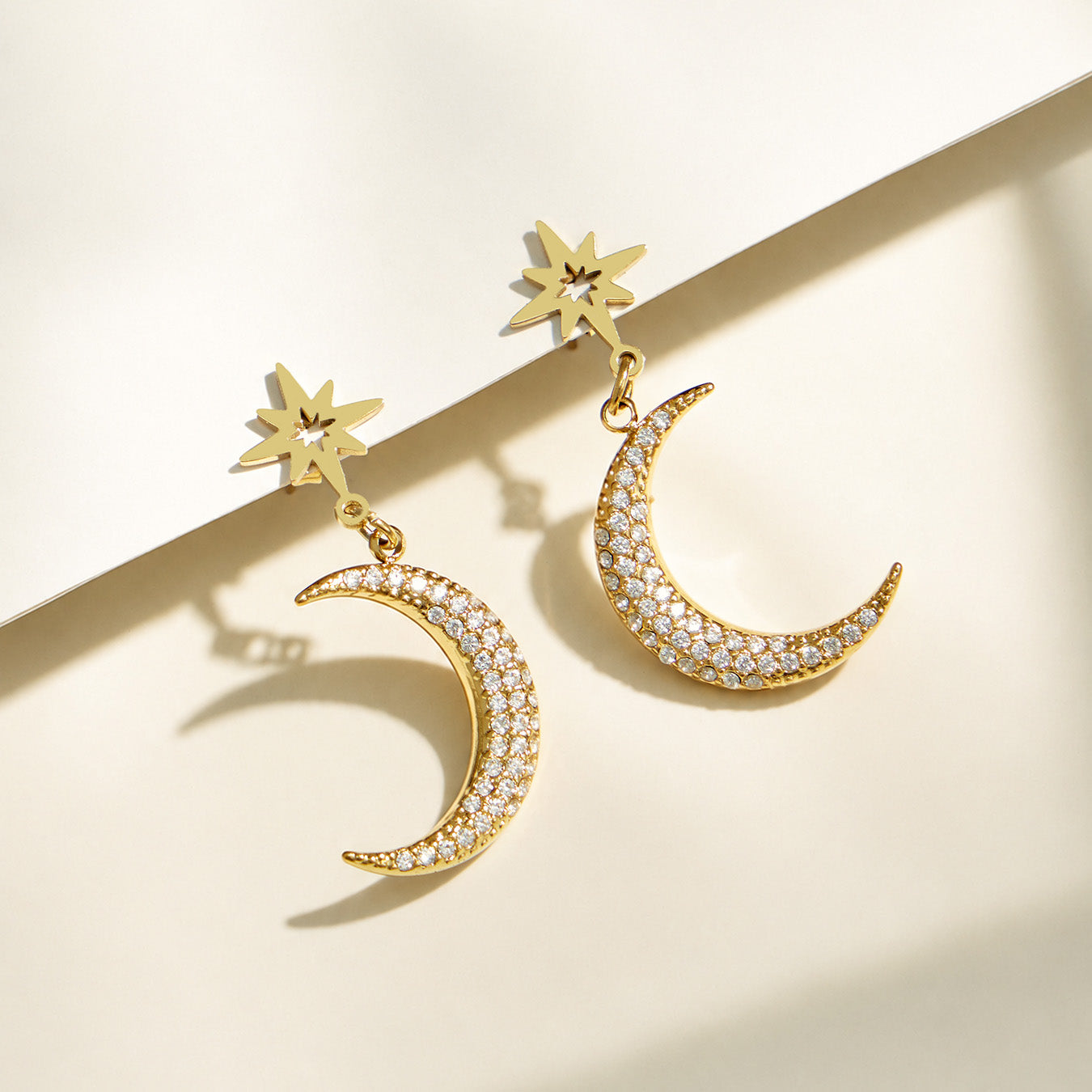 Close-up of gold star, crescent moon and clear zircon details from the celestial jewelry collection