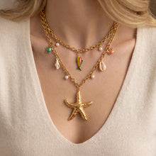 Gold starfish charm necklace with colorful sea life accents styled on model