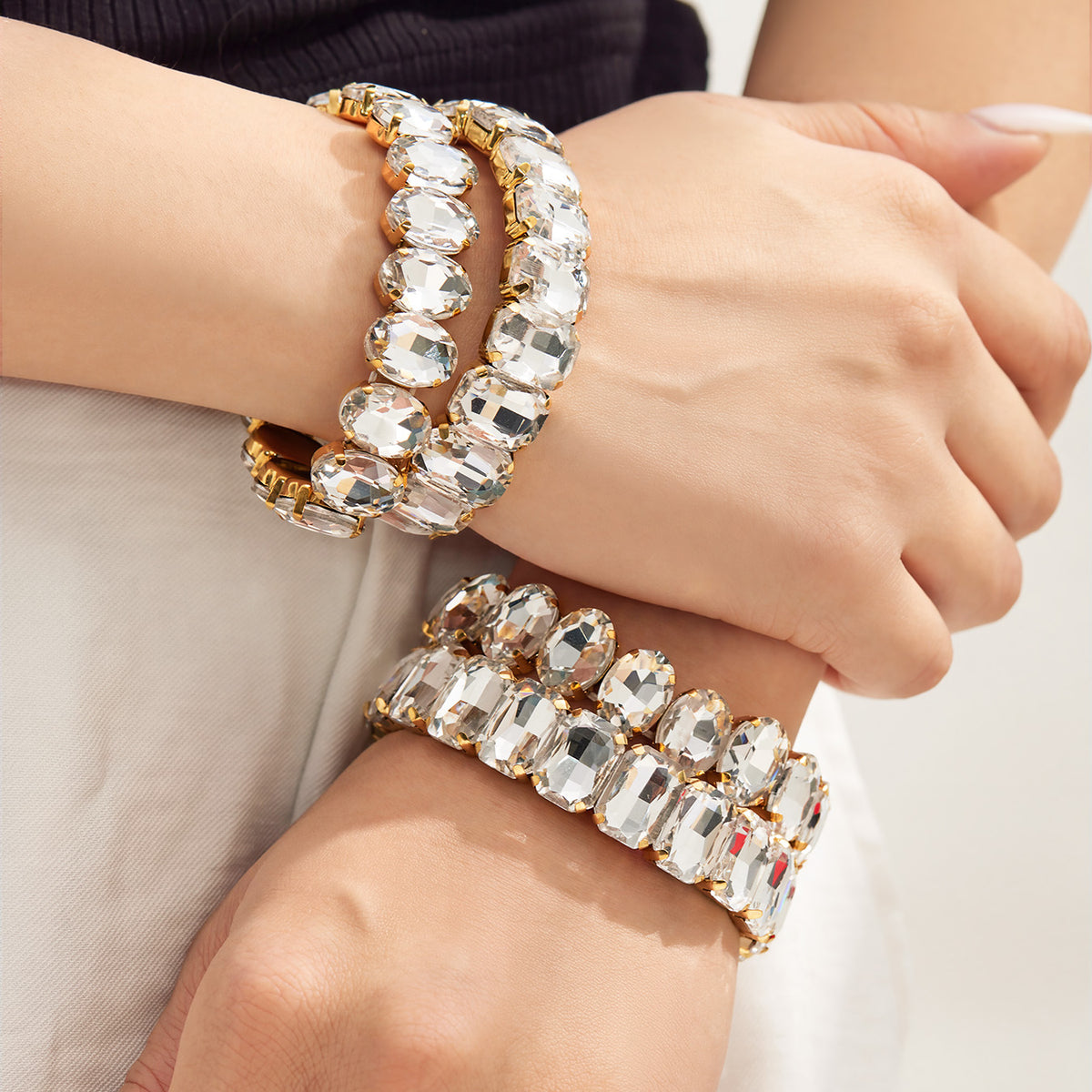 Statement gold-tone rhinestone stretch bracelets stacked together on wrists
