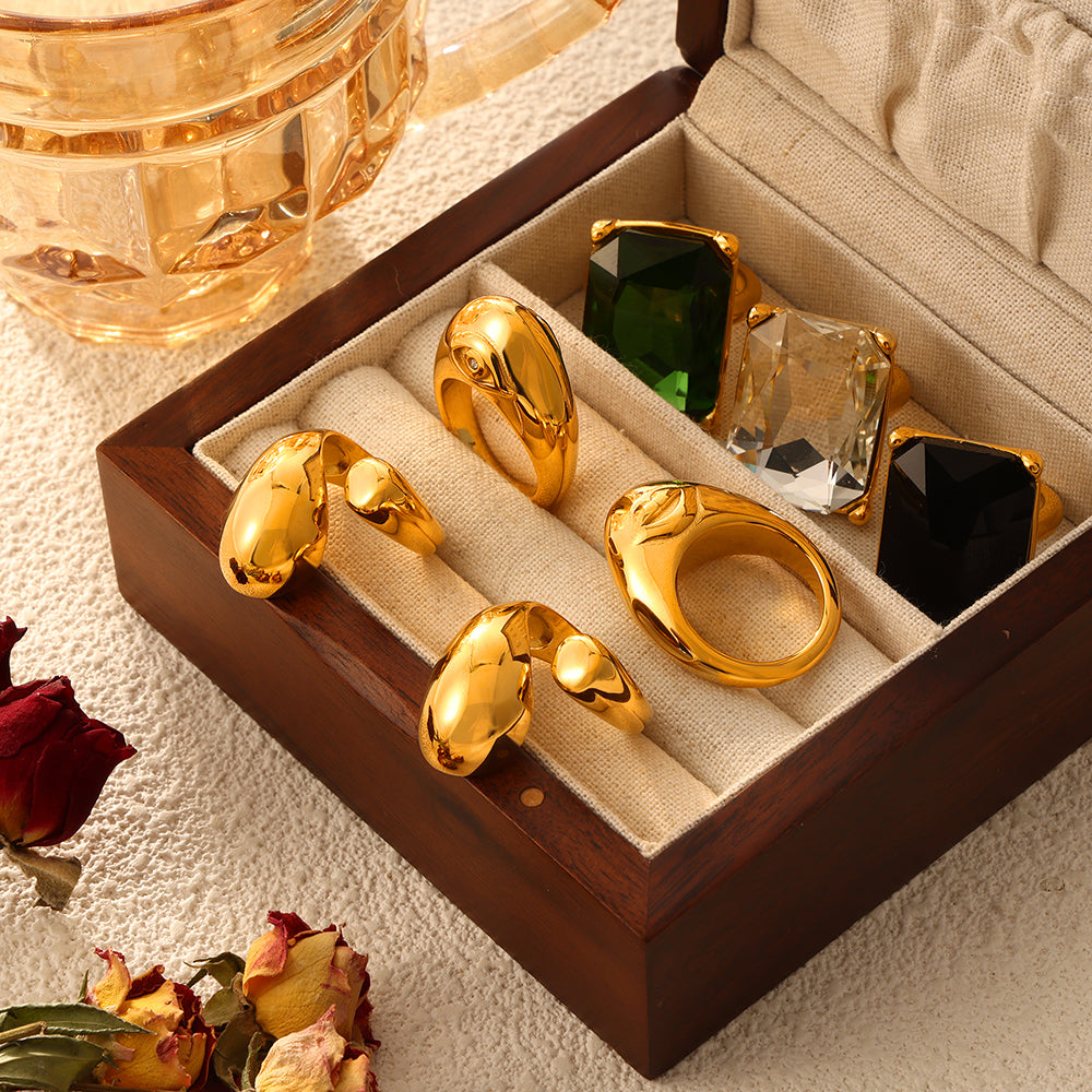 Mixed sculptural and rectangular stone statement rings displayed in an open jewelry box