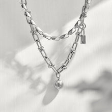 Model wearing a polished steel ball lock chain link necklace in a layered jewelry look