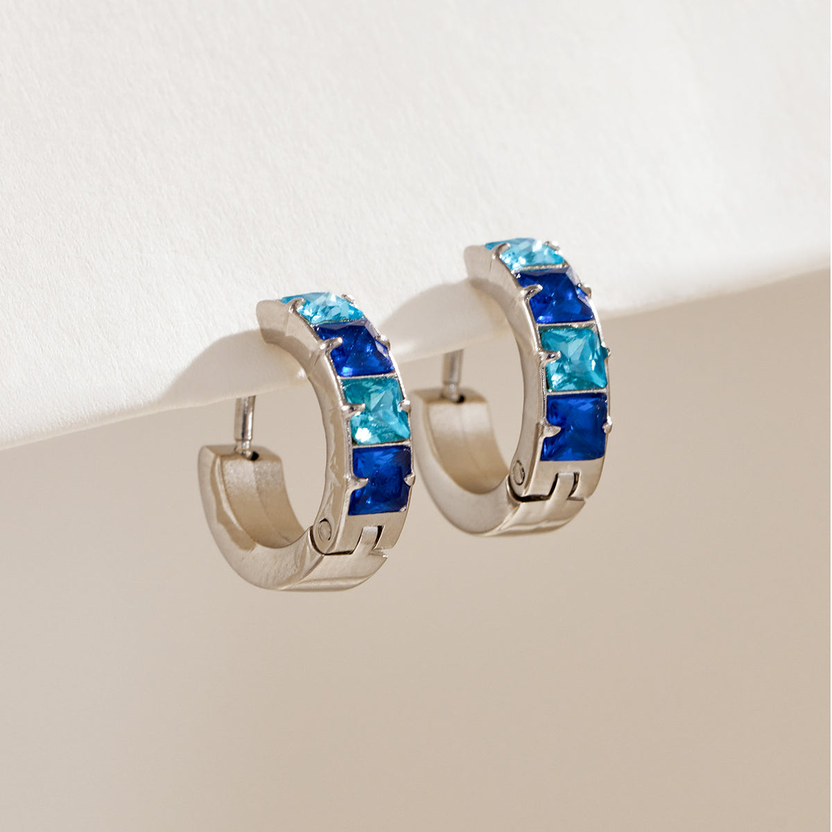 Steel-tone stainless steel huggie hoop earrings with blue cubic zirconia