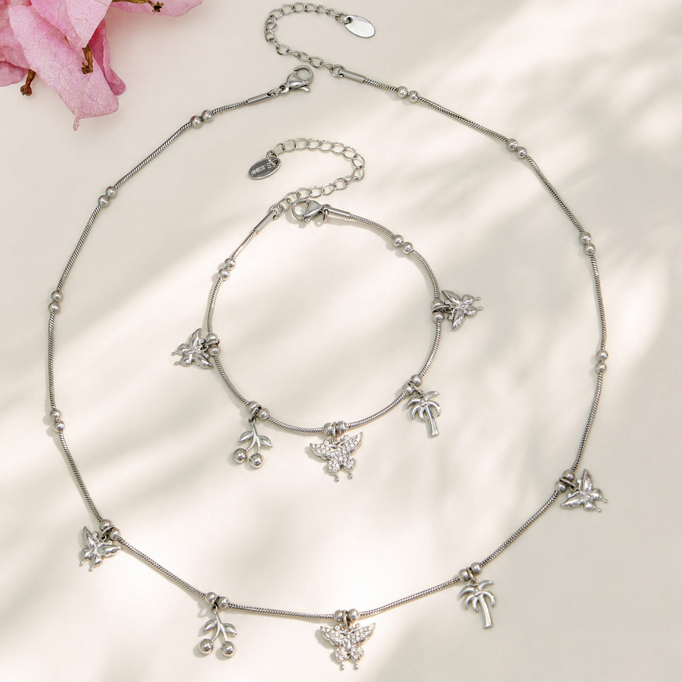Polished steel butterfly charm necklace and bracelet arranged in a circular display