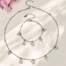 Polished steel butterfly charm necklace and bracelet arranged in a circular display