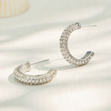 Steel-tone C-shaped cubic zirconia hoop earrings in a product display
