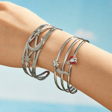 Polished steel celestial and chili pepper cuff bracelets worn together on a model wrist