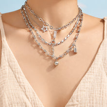Model wearing layered polished steel chain link and lariat necklaces