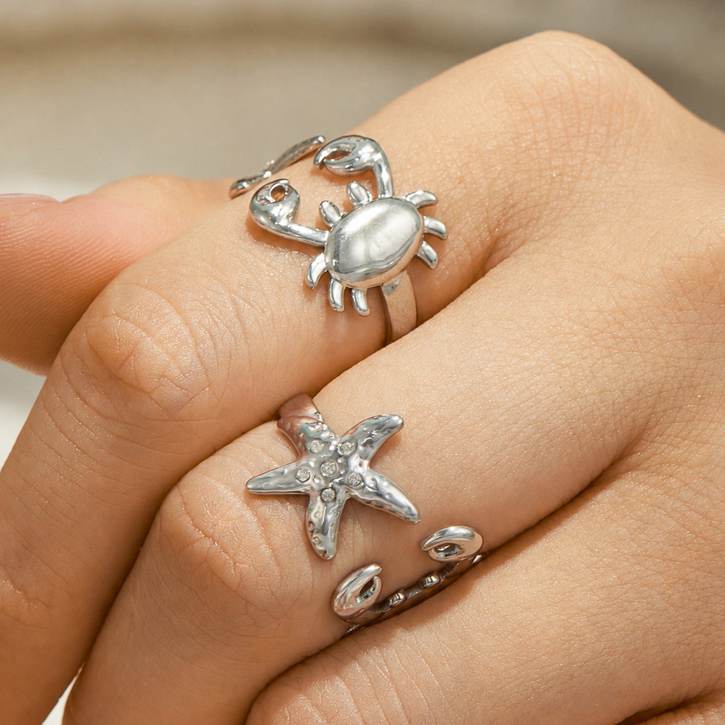 Model wearing polished steel crab and starfish rings in 316L stainless steel