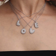Layered steel tone iced out initial letter necklaces with zircon pendants worn by model