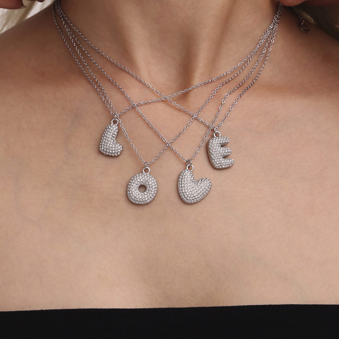 Layered steel tone iced out initial letter necklaces with zircon pendants worn by model