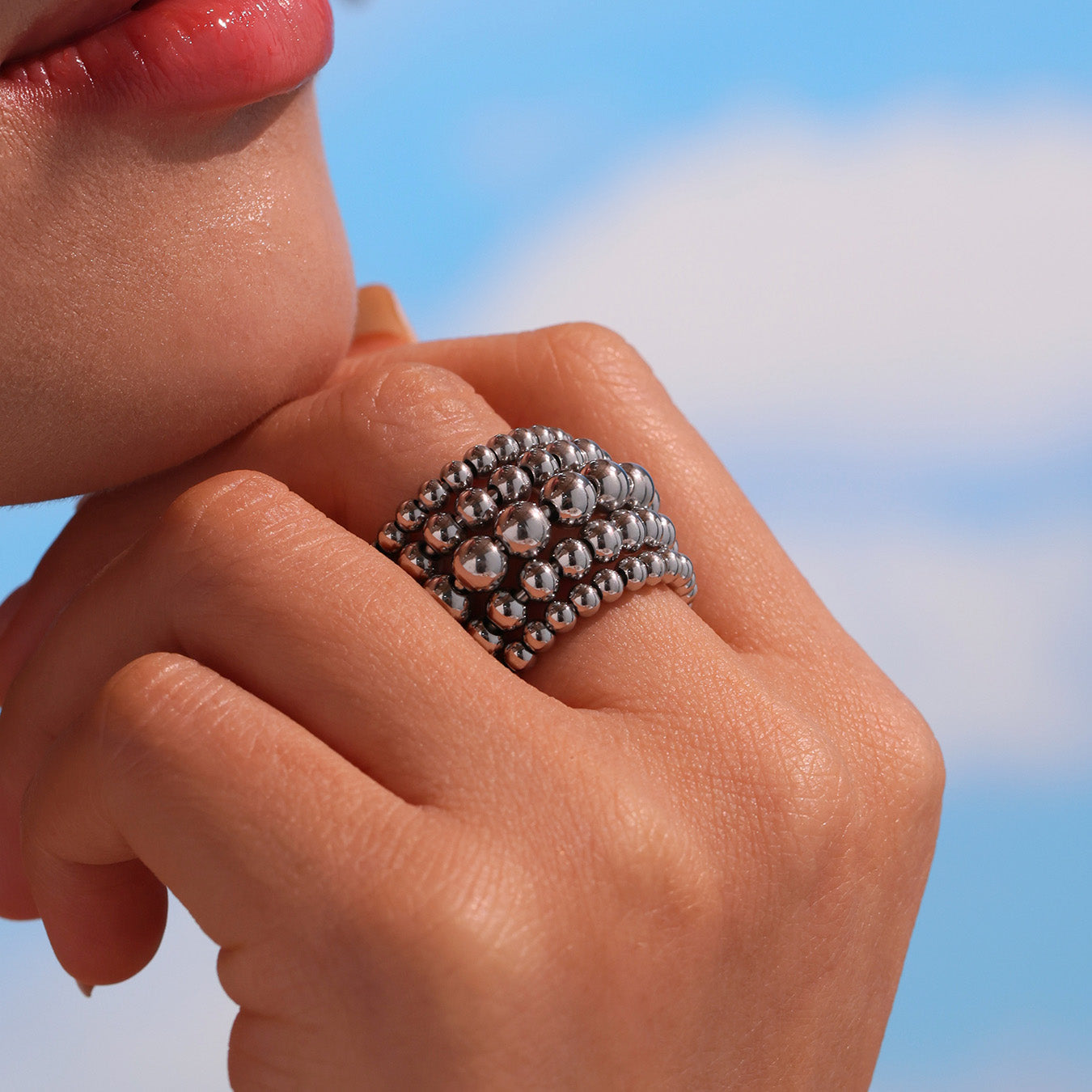 Close-up of steel tone multi-row beaded stainless steel ring worn on hand