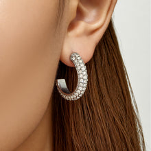 Model wearing steel-tone C-shaped pavé cubic zirconia hoop earrings