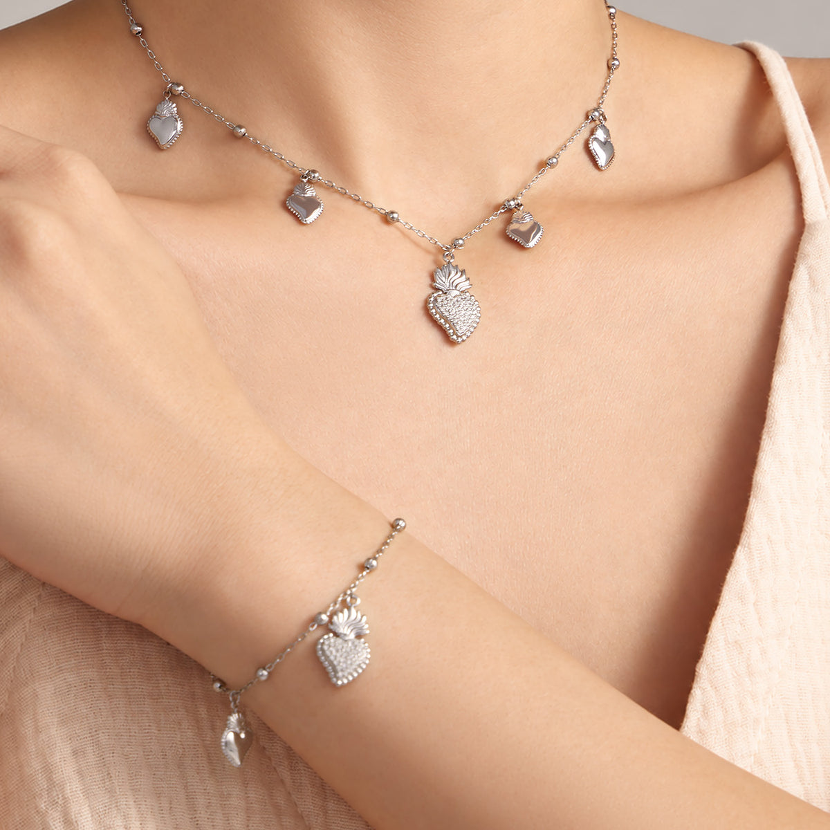 Steel-tone heart zircon necklace and matching bracelet styled together on model