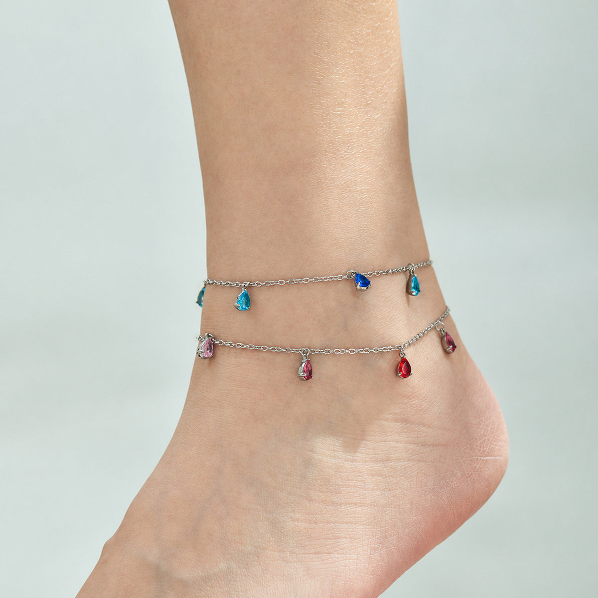 Steel-tone teardrop zircon anklets styled together around the ankle