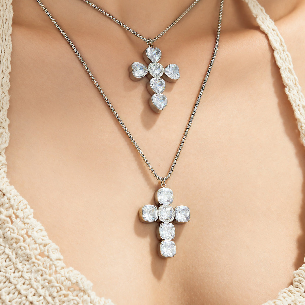 Steel-tone square and heart zircon cross necklaces layered on model