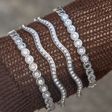 Steel tone zircon bangle bracelet stack worn over brown knit sleeve with wavy cuff bracelets and round zircon bracelet