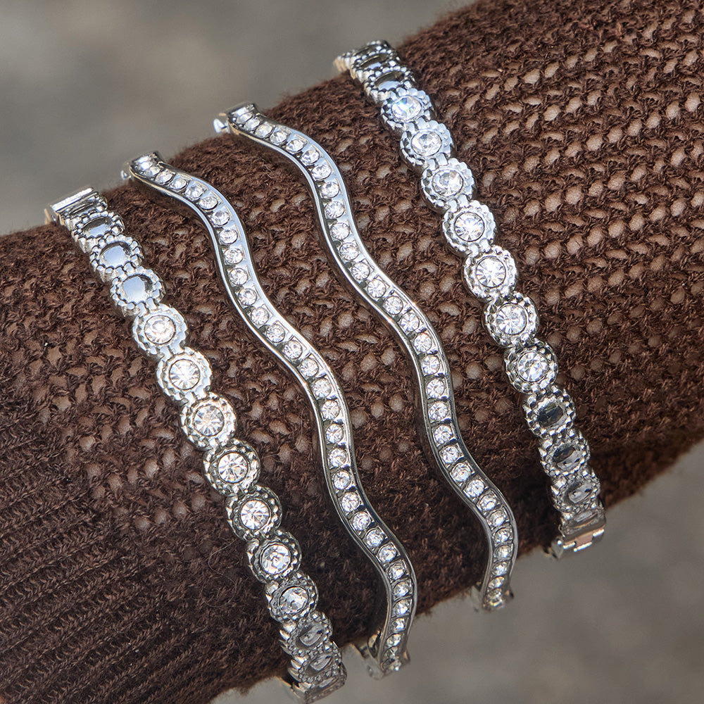 Steel tone zircon bangle bracelet stack worn over brown knit sleeve with wavy cuff bracelets and round zircon bracelet