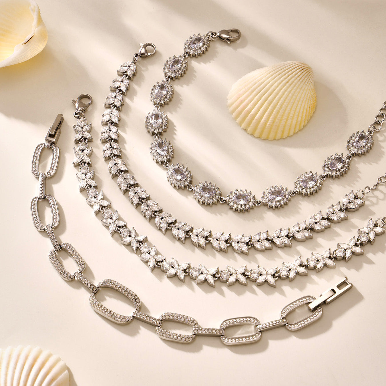 Polished steel zircon tennis, floral and oval link bracelets arranged in a flat lay