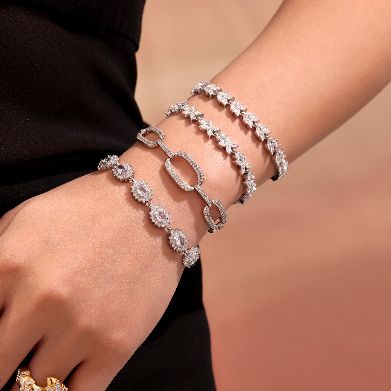 Model wearing a stack of polished steel zircon tennis and link bracelets