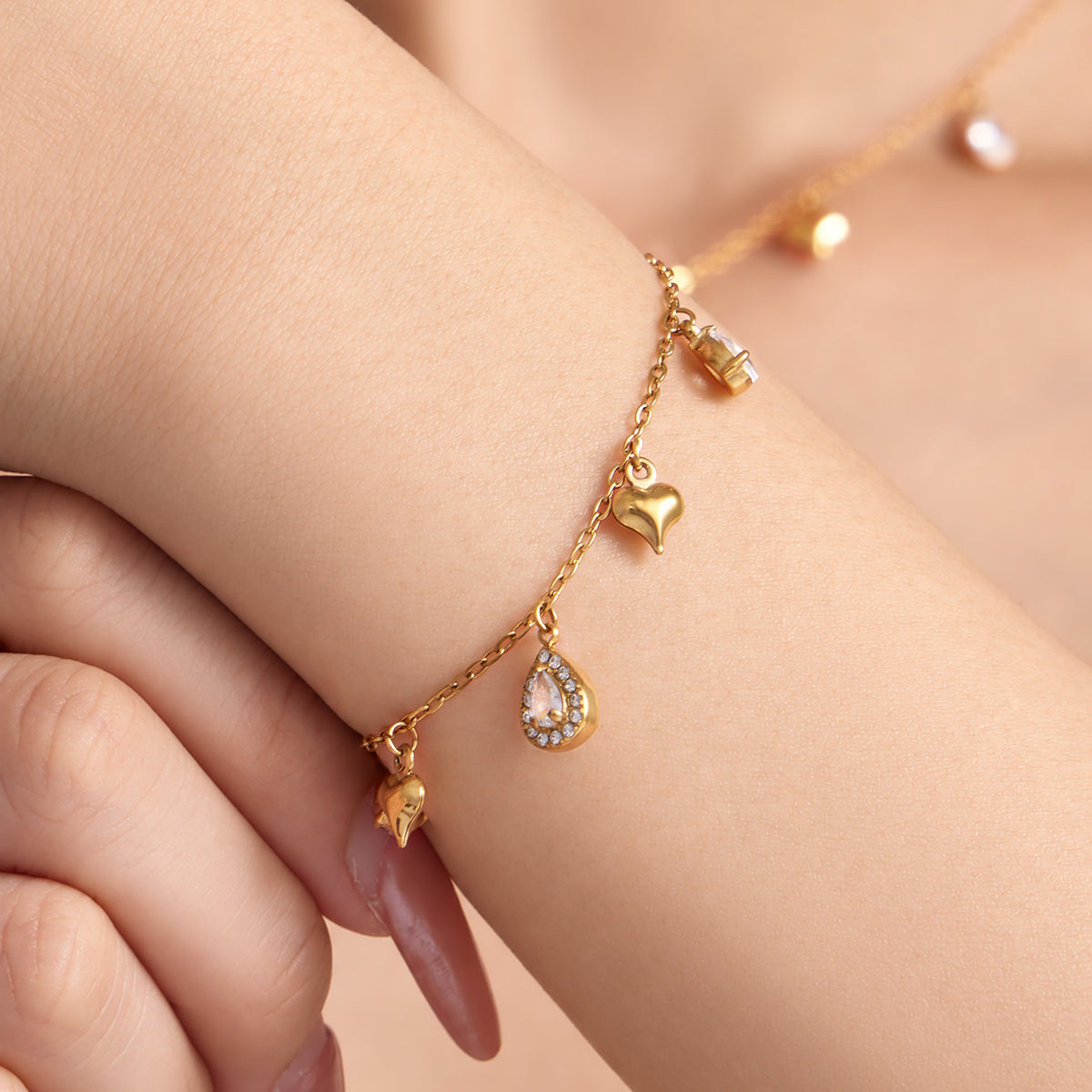 Dainty heart charm bracelet with clear teardrop zircon accents worn on wrist
