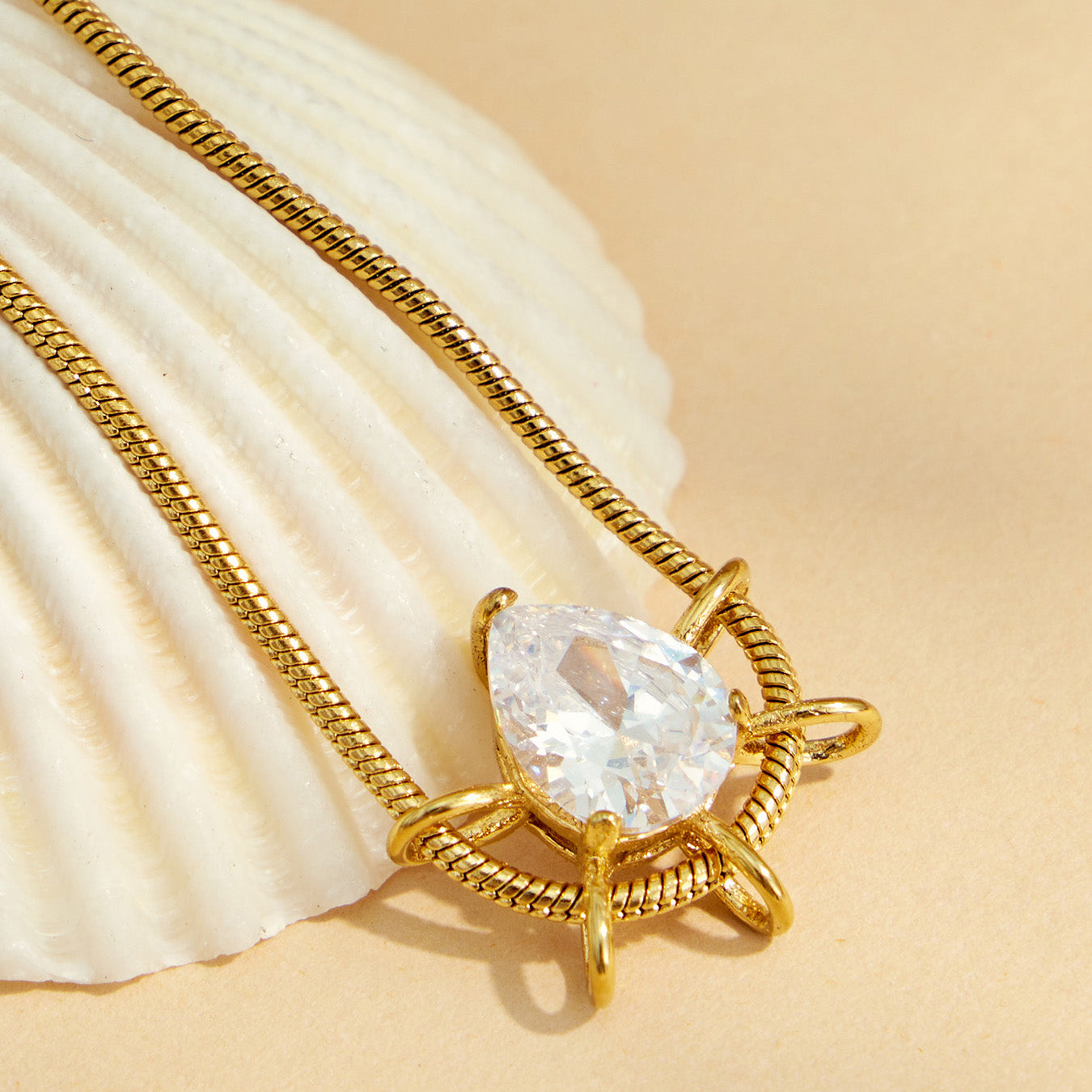 Close-up of a teardrop zircon pendant necklace displayed beside pleated fabric