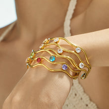 Model styling a three-layer open bangle with layered jewelry