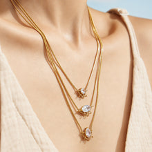 Close-up of a model wearing three layered zircon pendant necklaces at different lengths