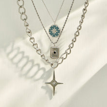 Three steel-tone geometric pendant necklaces arranged in a layered flat-lay display