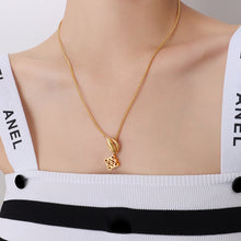 Close-up of a gold-tone toggle clasp pendant necklace worn on the neck