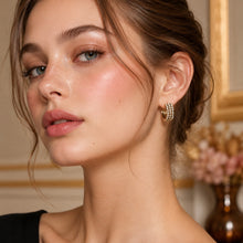 Side-profile model wearing gold triple-row pavé huggie earrings