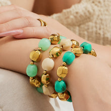 Close-up of turquoise and cream resin bead bracelets stacked on the wrist with polished metal spacer beads.