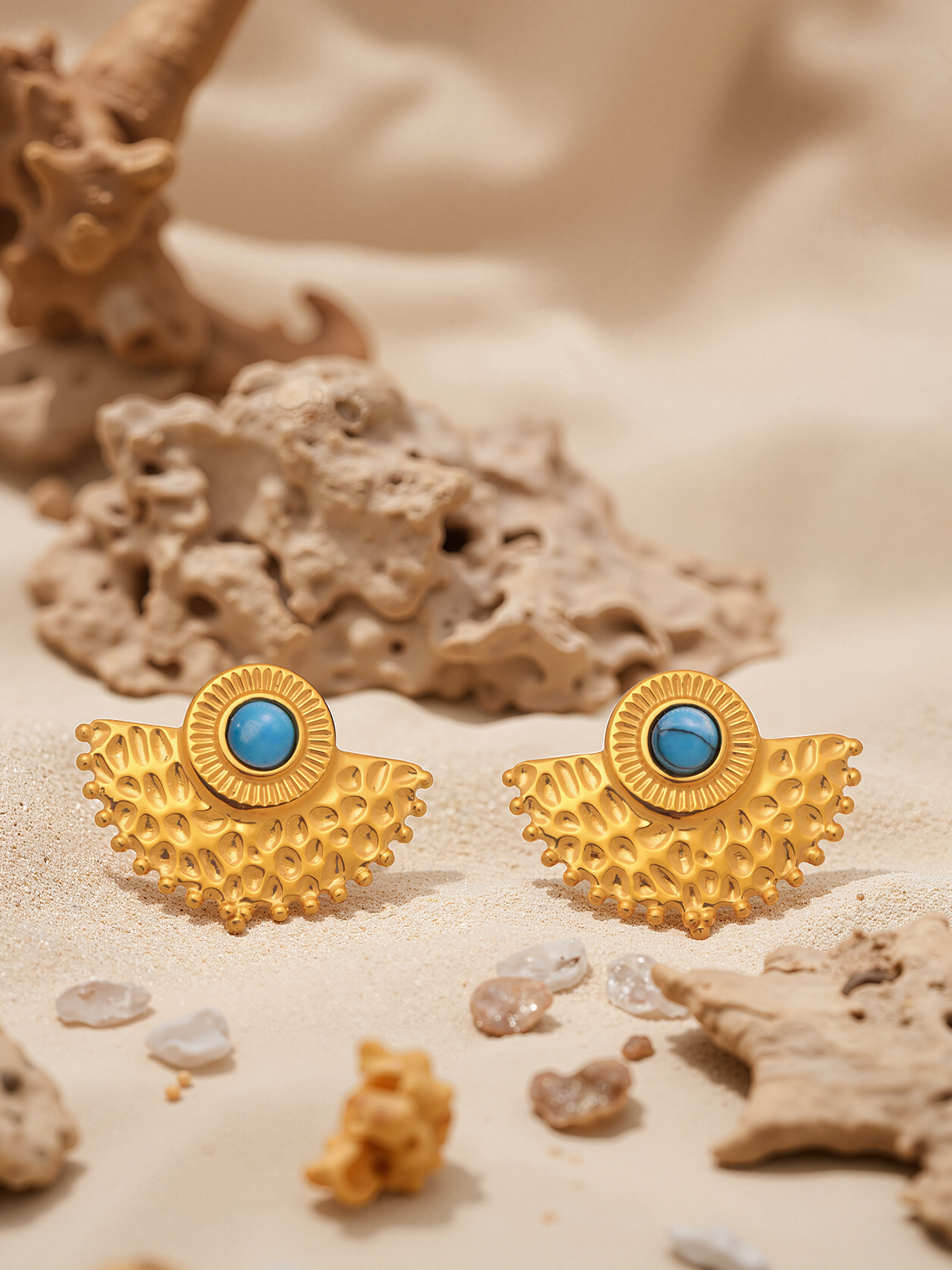 Gold turquoise peacock fan stud earrings flat lay with beach stones and driftwood