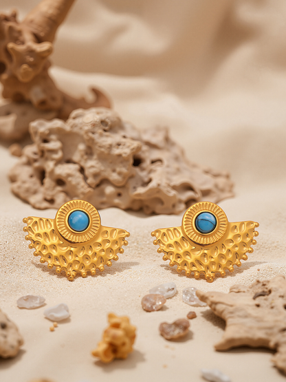 Gold turquoise peacock fan stud earrings flat lay with beach stones and driftwood
