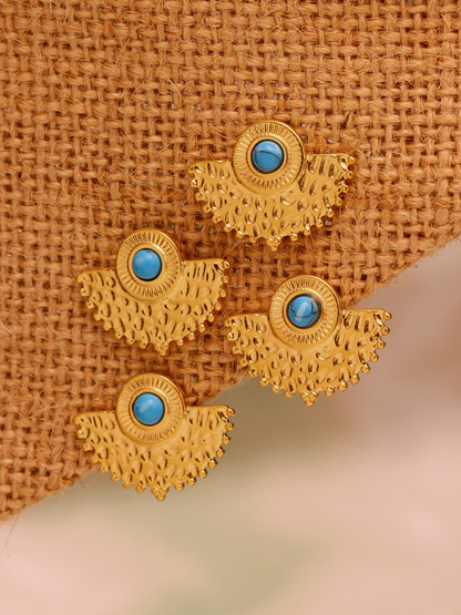 Turquoise peacock fan earrings displayed on woven straw texture for vacation jewelry