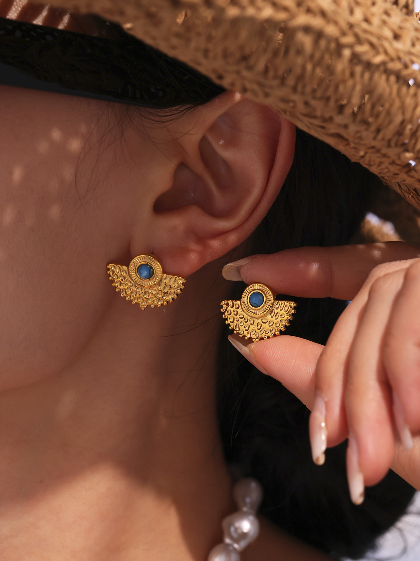 Turquoise peacock fan stud earrings worn with straw hat for resort boutique styling