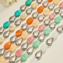 Close-up of colorful oval resin bead strands with polished steel-tone accents arranged in parallel rows