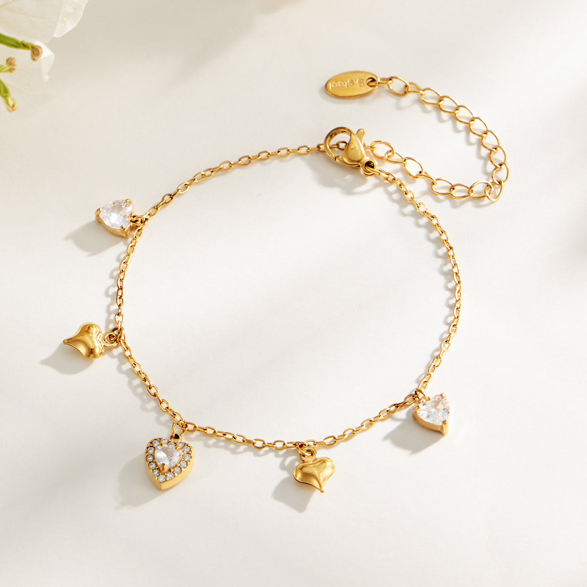 Gold heart zircon charm bracelet with adjustable chain displayed on a light background