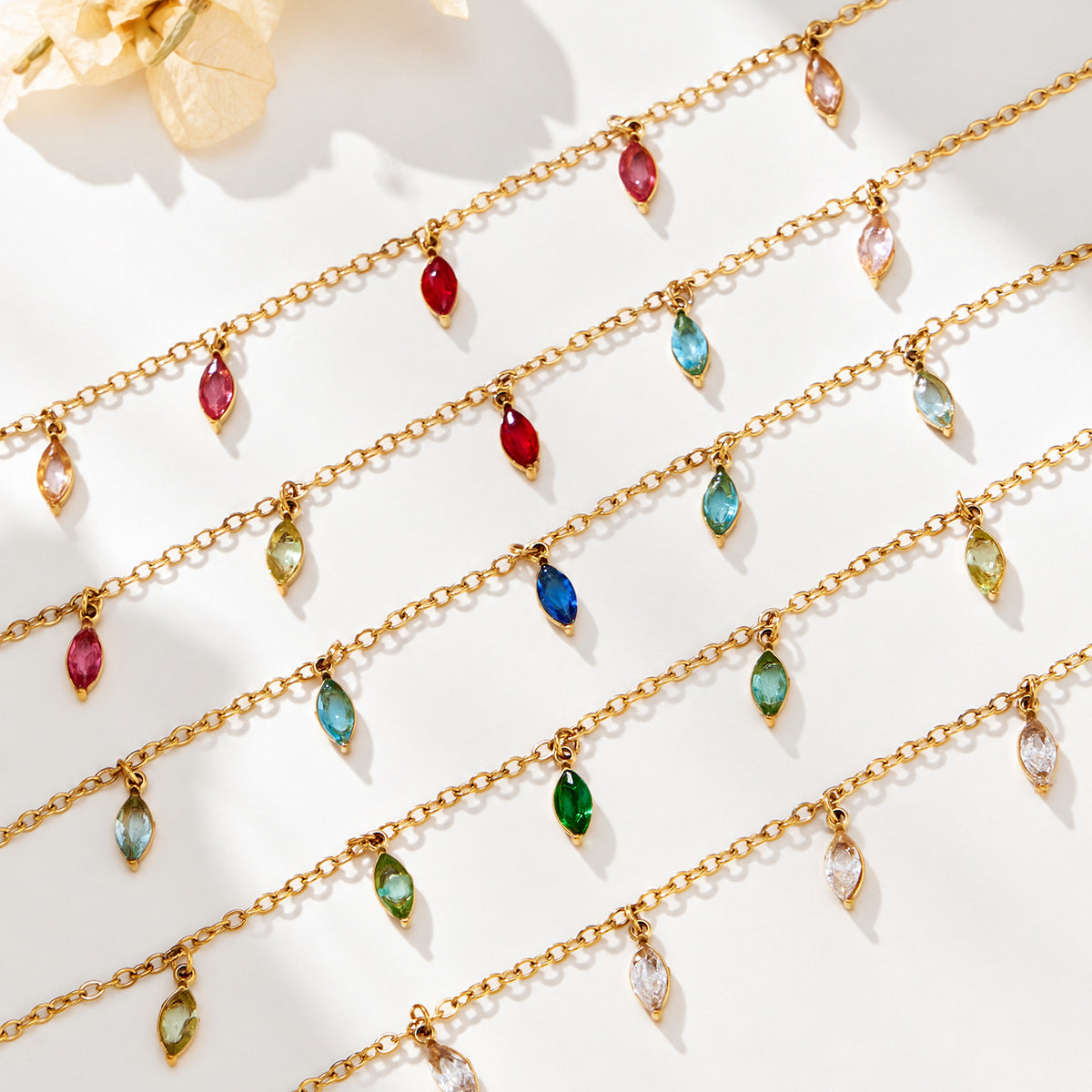 Fine gold-tone chains arranged diagonally with dangling red, blue, green and clear pointed teardrop charms.